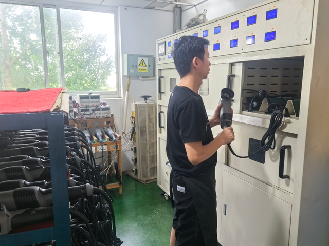 Man using a dual action polisher in a workshop, surrounded by various car polishing equipment and tools