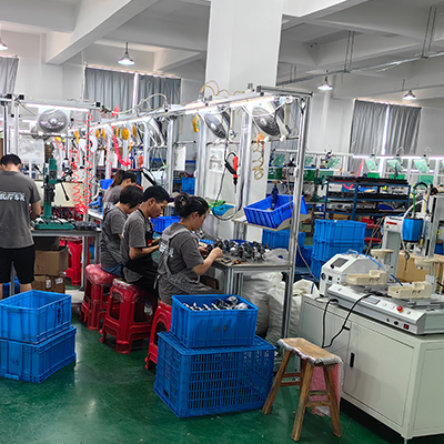 Factory workers diligently assemble car polishers, including dual action and rotary models, amidst organized workstations and equipment.